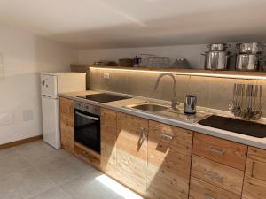 a kitchen with wooden cabinets and a sink and a refrigerator at Xenìa in Villalago
