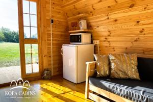 a living room of a log cabin with a refrigerator and a microwave at KOPA CABINS seaside stay in Nida +20 photos