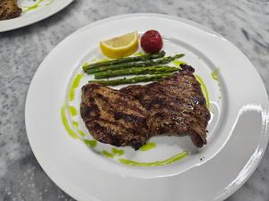 a plate of food with a piece of meat and asparagus at Serenata Korcare Resort in Tirana