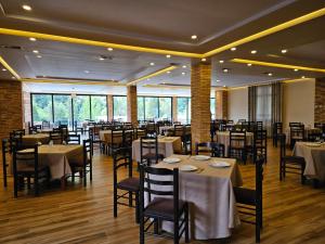 a restaurant with tables and chairs in a room at Serenata Korcare Resort in Tirana