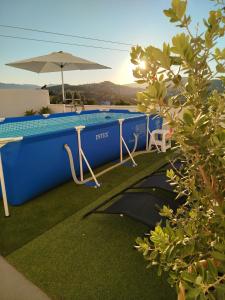 a swimming pool with two chairs and an umbrella at La Venta Casa Rural in Benitachell