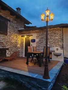 a wooden deck with a table and a street light at Chalet La montagne enchantée in San Damiano Macra
