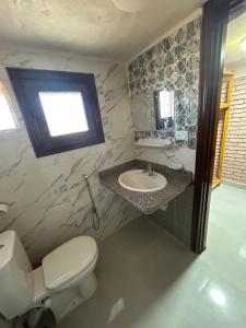 a bathroom with a toilet and a sink and a window at Free Beach Camp in Nuweiba‘ el Muzeinah