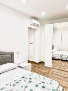 a white bedroom with a bed and a mirror at Menotti Appartment in Avola