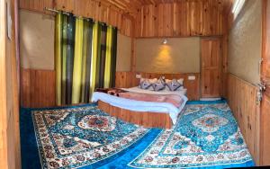 a bedroom with a bed and a rug on the floor at Shikhar cottage in Jibhi