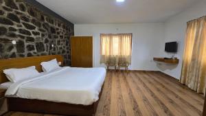a bedroom with a large bed and a stone wall at Vedhas Holidays in Kodaikānāl