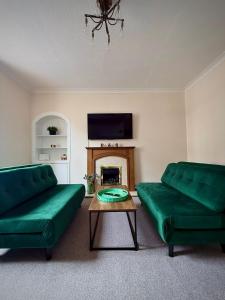 a living room with two green couches and a fireplace at Coorie in Inverness