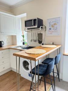 a kitchen with a table with a microwave and a washing machine at Coorie in Inverness +15 photos