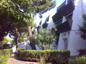 a man walking past a white building with flowers at Residence MARE App Alga 24 in Lido delle Nazioni