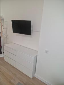 a white dresser with a flat screen tv on a wall at M&M Apartamentai in Klaipėda
