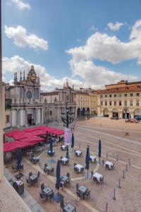 a city square with tables and umbrellas in front of a building at San Carlo Suite Torino in Turin