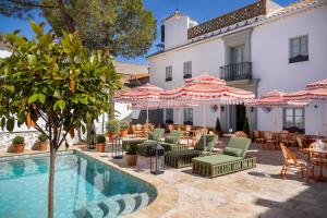 a hotel with a pool and chairs and umbrellas at Hotel Boutique Casa Treviño in Campo de Criptana