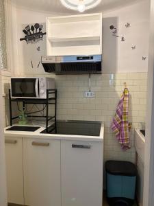 a kitchen with white cabinets and a microwave at Appartamento Iris in Torre Pellice +12 photos