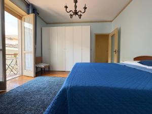 a bedroom with a blue bed and a chandelier at Appartamento Iris in Torre Pellice