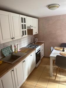 a kitchen with white cabinets and a stove top oven at Domek Pod Sosnami D in Krasnobród