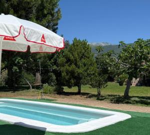 a blue swimming pool with an umbrella and an umbrella at La Celestina in Candeleda
