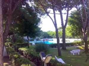a park with a swimming pool and trees and benches at Residence MARE App Alga 24 in Lido delle Nazioni