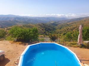 a blue swimming pool with a view of mountains at Cortijo Saucillo in Albondón +9 photos