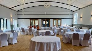 a room filled with white tables and chairs at The Raven Hotel in Corby