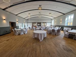 a banquet hall with white tables and white chairs at The Raven Hotel in Corby