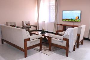 a living room with chairs and a tv on a wall at Kiliheights Getaway in Sanya Chini Station