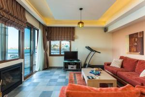 a living room with a red couch and a tv at Cavo Seaside Suites in Rethymno