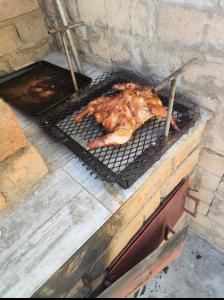 a piece of meat cooking on a grill at A Great Guest House Grootfontein in Groutfontein