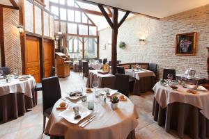 a restaurant with white tables and chairs and windows at La Chaumière in Aubigny-sur-Nère