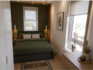 a bedroom with a green bed and two windows at Euforia Ma Apartment Sarajevo in Sarajevo