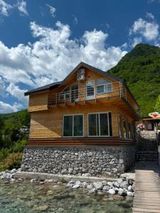 a wooden house sitting on top of a river at Guesthouse Kurora e Maleve in Ndërlysaj