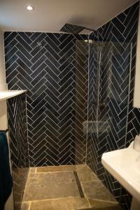 a bathroom with a black tiled shower with a sink at The Old Blacksmiths in Bridgnorth +19 photos