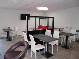 a dining room with black tables and white chairs at Hôtel de la baie de Paimpol in Ploubazlanec