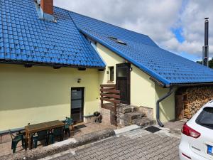 a house with a blue roof with a picnic table at Apartmán U Davida in Chvaleč