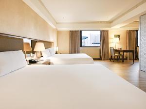 a large hotel room with two beds and a table at CHECK inn Taipei Neihu in Taipei