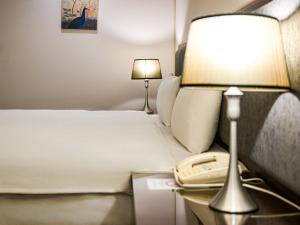a hotel room with a bed with a lamp and a phone at CHECK inn Taipei Neihu in Taipei