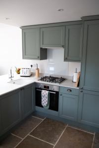 a kitchen with green cabinets and a stove top oven at The Old Blacksmiths in Bridgnorth