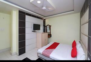 a bedroom with a bed with red pillows and a tv at Hotel Neelkanth in Lucknow