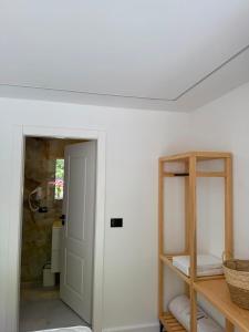 a room with a white wall with a shelf and a door at Guesthouse Kurora e Maleve in Ndërlysaj