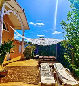 a patio with two lounge chairs and an umbrella at La Suite Soleil in Gujan-Mestras
