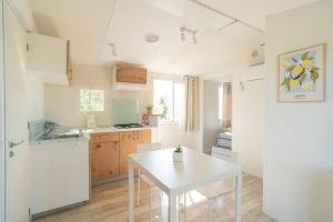 a kitchen with a white table and a white refrigerator at Agricamping L'Ibisco in Riotorto