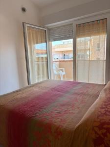 a bedroom with a large bed and a large window at Comfort Home in Capoterra