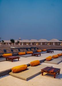 a pool with orange pillows and tables and chairs at Jaisalmer Villa Resort & Camp Jaisalmer in Jaisalmer