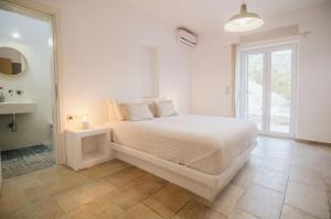 a white bedroom with a large bed and a window at Sea and Sun l in Mylopotas +76 photos