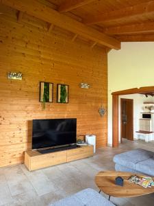 a living room with a flat screen tv on a wooden wall at Ferienhaus an der Drau in Sankt Oswald