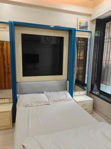 a bedroom with a large flat screen tv above a bed at Meenaji's home in Mumbai