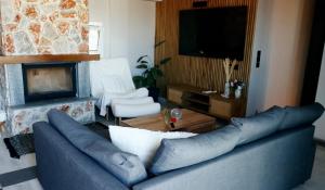 a living room with a blue couch and a tv at Mountain Aura - Stylish Escape in Kamarítsa