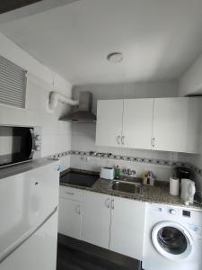 a white kitchen with a sink and a washing machine at Lorena in Salou