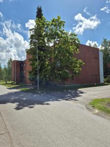 a tree is in front of a brick building at Apartment with private sauna in Loimaa