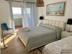 a bedroom with a bed and a chair and a window at Sea View urban apartment in Faro