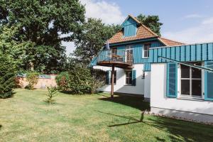 ein blau-weißes Haus mit einem Hof in der Unterkunft Haus am Schilf in Wieck